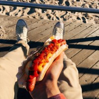 eating famous new york hot dog at coney island boardwalk, personal perspective - junk food stock pictures, royalty-free photos & images