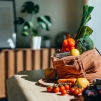 eco-friendly reusable shopping bag with multi-coloured fresh vegetables and groceries on the table at home. shopping with reusable grocery bag for plastic free and waste-free life. responsible shopping. zero waste and sustain