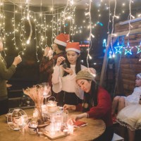 eine gruppe asiatischer chinesischer junger erwachsener, die sich auf ihr weihnachtsessen vorbereiten, zünden kerzen an und passen das weihnachtsliche lichterkettenlicht im vorgarten des hauses an. - garden decoration stock-f