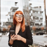 elegant businesswoman arranging meeting on smartphone while walking in city - fashion stock pictures, royalty-free photos & images