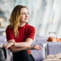elegant woman smiles while waiting in an airport lounge - travel stock pictures, royalty-free photos & images
