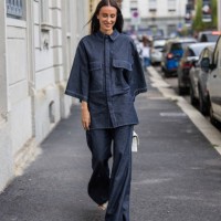 Elvira Jain wears oversized dark navy denim button shirt with short sleeves, flared jeans, white bag outside Calcaterra during the Milan Fashion Week...