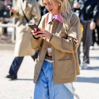 Emili Sindlev on the phone wears beige jacket, denim jeans shorts, striped brown polo outside Casablanca during the Womenswear Fall/Winter 2025/2026...