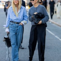 Emili Sindlev wears blue button shirt, beret, denim jeans, Hermes bag & Claire Rose Cliteur wears grey cardigan, black bag, pants outside Cos during...