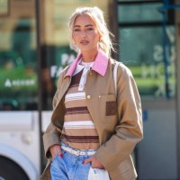 Emili Sindlev wears gold earrings, light pink t-shirt, light brown dark brown white striped polo shirt, dark brown dark pink leather collar oversized...