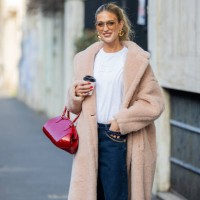 Emili Sindlev wears salmon colored coat, white Miu Miu shirt, sunglasses, golden earrings, red Louis Vuitton bag, denim jeans outside Max Mara during...