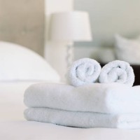 empty room, hospitality and clean towels on a bed at a condo, resort or motel. hotel, attention to detail and preparation for customers at a spa with luxury soft fabric, linen and cotton cloth. - home decoration stock picture