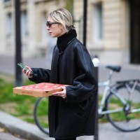 Emy Venturini wears sunglasses from Miu Miu, a gold earrings, a black turtleneck pullover from Cos, a black shiny leather with black sheep interior...