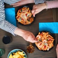 enjoying delivery bowls like pesto cavatappi bowl, meatballs bowl, pasta fresca bowl and grilled chicken caesar salad bowl - junk food stock pictures, royalty-free photos & images