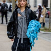 Erika Boldrin wears grey cut out top, blue bag, leather jacket outside Stella McCartney during Womenswear Spring/Summer 2025 as part of Paris Fashion...