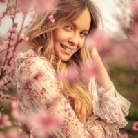 erstaunliche junge frau posiert in aprikosenbaum obstgarten im frühling - fashion stock-fotos und bilder