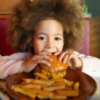 ethnic kid girl eating burger and chips - junk food stock pictures, royalty-free photos & images