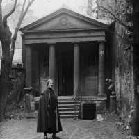 Ex-patriate American author and salon hostess Natalie Clifford Barney wears a cape and stands in front of a Greek-style temple in the garden of her...