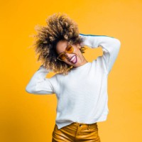 excited afro young woman dancing against yellow background - fashion stock pictures, royalty-free photos & images