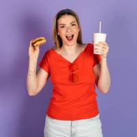 excited hungry pretty girl eats fast food, cheap burger, holds a cheeseburger and soda, open mouth. fast food and unhealthy diet. isolated on purple background. - junk food stock pictures, royalty-free photos & images