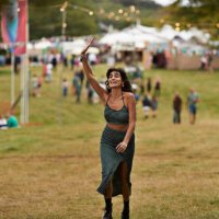 excited woman with raised hand walking at park - concert stock pictures, royalty-free photos & images