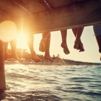familie sitzt am pier am meer - travel stock-fotos und bilder