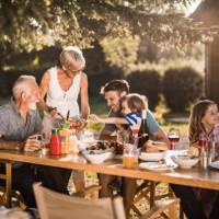 famille élargie heureuse parlant tout en ayant leur déjeuner dans la cour avant. - garden decoration photos et images de collection