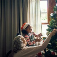 family, christmas tree and decor with a mature woman and child preparing for festive season with love. grandmother, granddaughter and decorating an xmas tree with ornaments and bauble in family home - home decoration stock pi