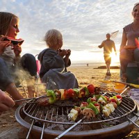 family having bbq on beach at sunset - food stock pictures, royalty-free photos & images