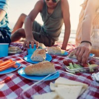 family having summer picnic breakfast on the beach - food stockfoto's en -beelden