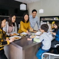 family of four enjoying chinese takeout in modern kitchen - junk food stock pictures, royalty-free photos & images