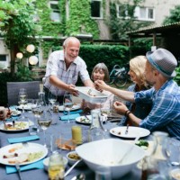 family sharing food at bbq in courtyard together - food stockfoto's en -beelden