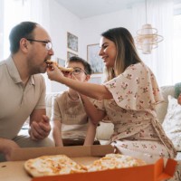 family with two children eating pizza in front of the tv in living room at home - junk food stock pictures, royalty-free photos & images