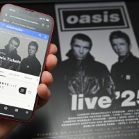 Fan uses a smart phone to access an on-line ticket sales website to purchase tickets for Oasis' 