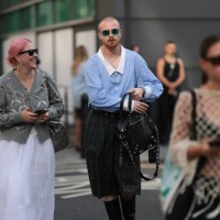 Fashion Show Guest was seen wearing black leather boots, oversized black and white checked shorts with a black belt, green shades, a black bag with...