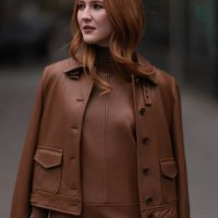 Fashion week guest is seen wearing a brown short dress with pockets, including a brown turtleneck with long sleeves and a brown leather jacket. She...