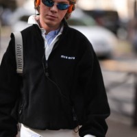 Fashion Week guest is seen wearing a complete outfit from Miu Miu, consisting of rimless oval sunglasses with blue mirrored lenses and silver metal...