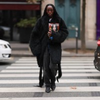 Fashion week guest is seen wearing a long black fur coat with an oversized look, with black baggy jeans and black boots during the Akris Show...
