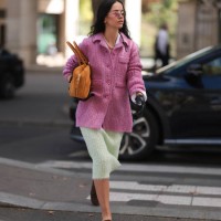 Fashion Week guest is seen wearing a pearl necklace, a complete outfit from Miu Miu, consisting of rimless oval sunglasses with pink mirrored lenses...