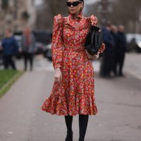 Fashion Week guest is seen wearing Balenciaga Outfit including black heels, black tights, a black bag, black shades and a red dress with white and...