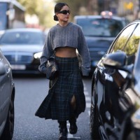 Fashion Week guest is seen wearing black chades, yellow gold earrings, a grey cropped Miu Miu shirt, a black Chanel bag and a green checked long...