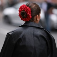 Fashion Week guest is seen wearing golden earrings, a shiny red ruffled scrunchie, and a black leather jacket before the Gestuz Show during the...