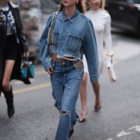 Fashion Week guest is seen wearing rectangular black sunglasses with wide temples; two gold hoop earrings; a matching two-piece consisting of a...