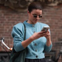 Fashion Week guest is seen wearing round sunglasses with fine silver metal frame, silver hanging earrings, a long-sleeves light blue cardigan with...