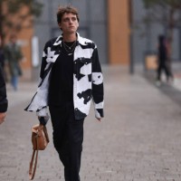 Fashion Week guest is seen wearing several golden necklaces, a jeans jacket with black/white cow print from Calvin Klein Jeans, underneath a black...