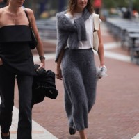 Fashion Week guest is seen wearing thin golden necklaces; a grey mohair wool two-piece-suit, consisting of a pullover and a midi skirt; a white plain...