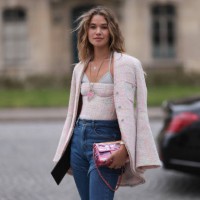Fashion Week Guest seen wearing denim blue jeans, a white bralette, rose Chanel off shoulder top, matching rose Chanel blazer jacket and a pink...