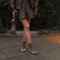 Fashion Week Guest was seen wearing a white top and a brown leather skirt and jacket, brown socks, and a brown Hermey Kelly bag as well as alaia...