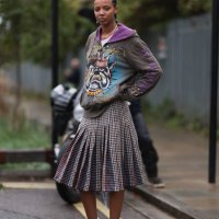 Fashion Week Guest was seen wearing black leather loafer, white Holzweiler socks, braids, a green and brown skirt, a white tank top and a grey-brown...