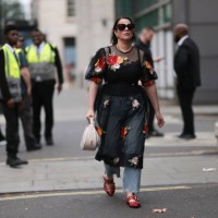 Fashion Week Guest was seen wearing red leather shoes, a denim jeans, abbeige bag, dark shades, a black top under a black transparent dress with...