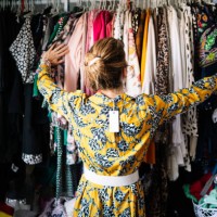 fashionable blond woman in new yellow dress choosing from clothes rack at apartment - fashion stock pictures, royalty-free photos & images