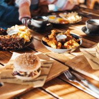 fast food, lunch or dinner on table at restaurant, people eating for nutrition and wellness with time together. catering, hospitality and cuisine with burger, chicken and ribs for protein at diner - junk food stock pictures, 