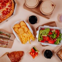 fast foods and vegetable salad near coffee cups against beige background - junk food stock pictures, royalty-free photos & images