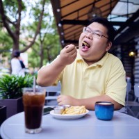 fat chinese man eating french fries - junk food stock pictures, royalty-free photos & images