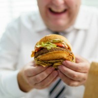 fat man eating cheeseburger. - junk food stock pictures, royalty-free photos & images